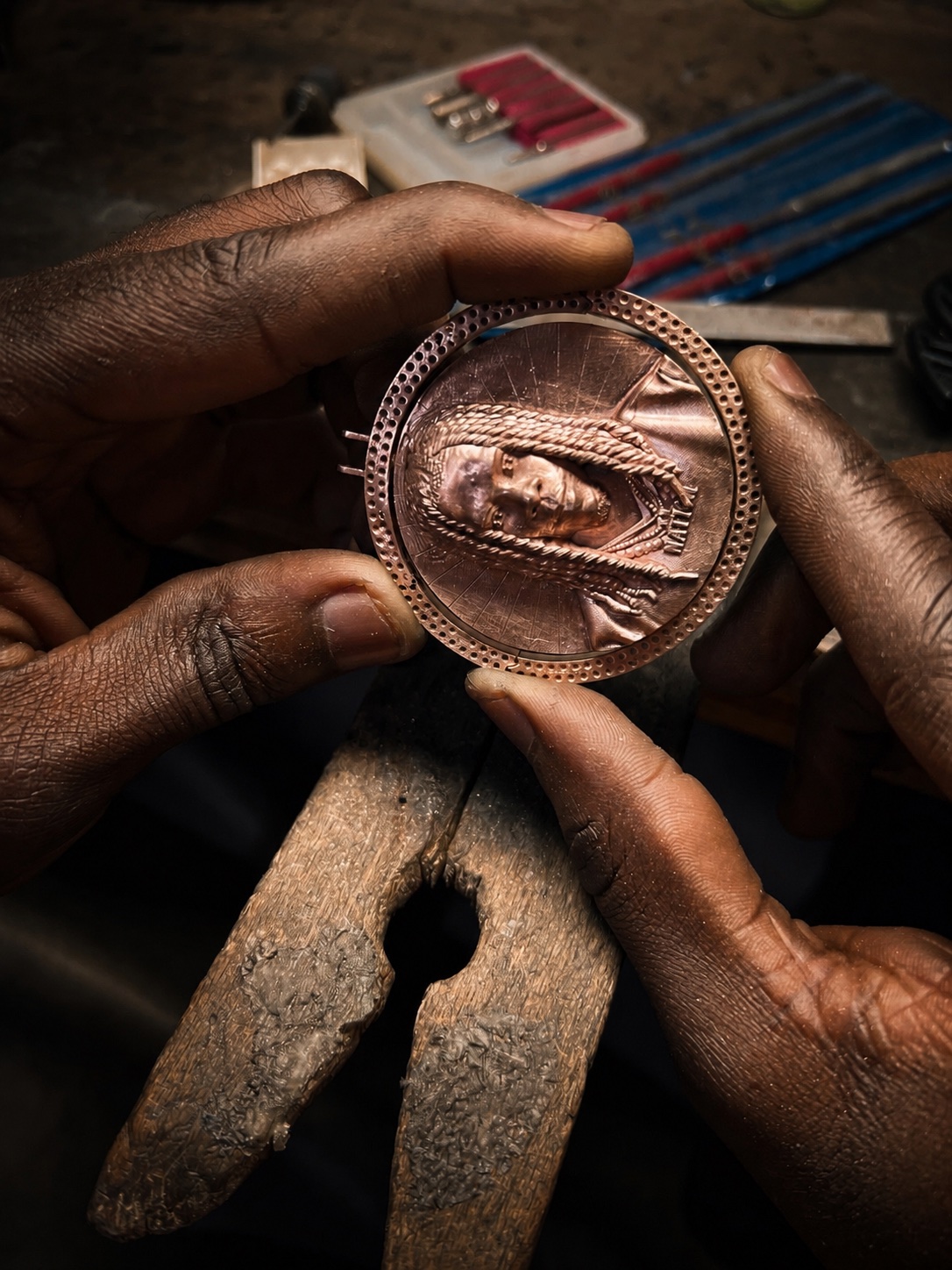 Erick Kraftsman holding a portrait pendant during production in Ghana
