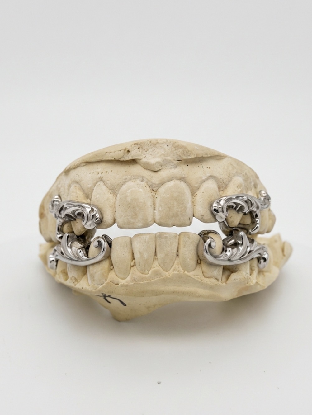 Sculptural silver Black Sherif grillz fitted on a dental model