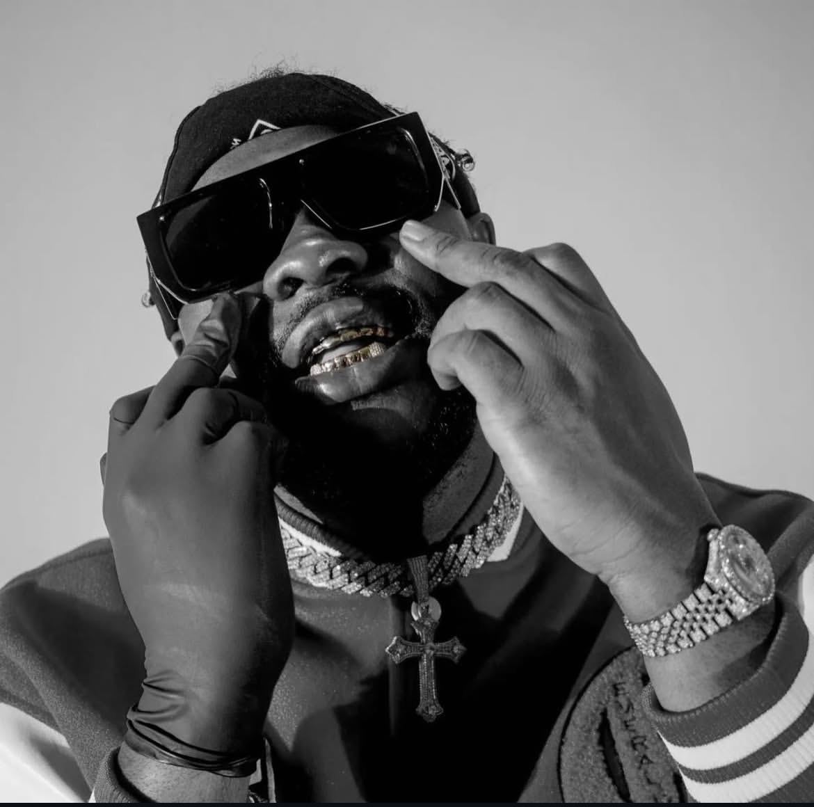 Medikal wearing sunglasses, grillz and layered diamond jewellery