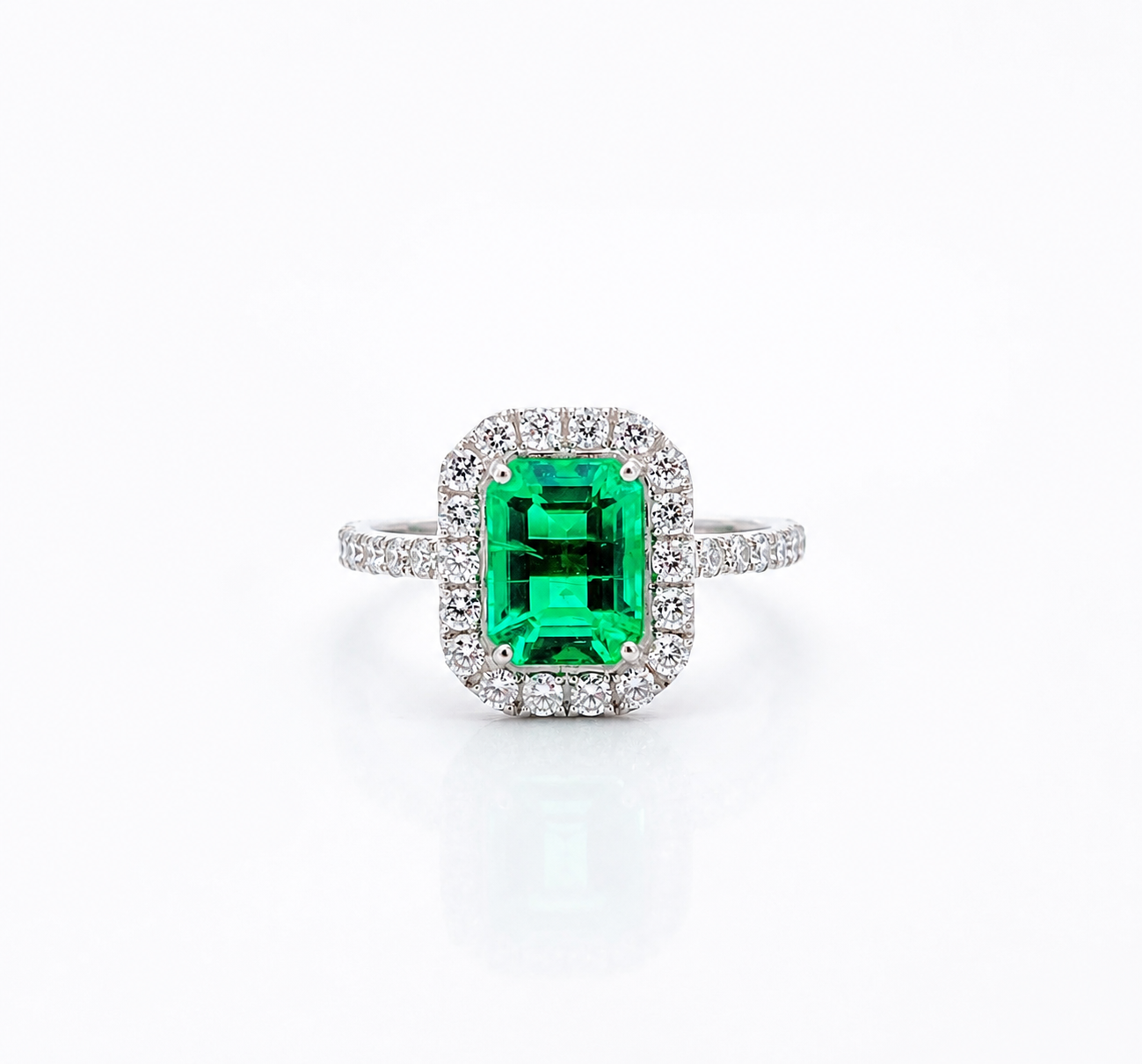 Front view of a ring with a rectangular green centre stone and surrounding clear stones